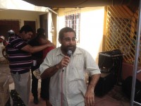 Pastor Dariosvaldo anuncia o Evangelho; Ao fundo, voluntário ora por folião