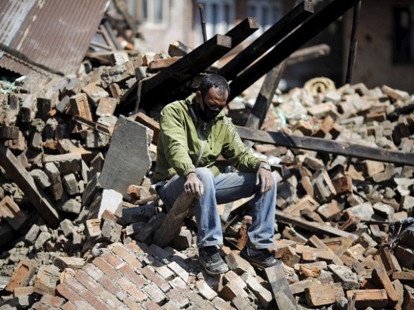 Homem desolado sobre escombros de edifício que desabou durante o terremoto