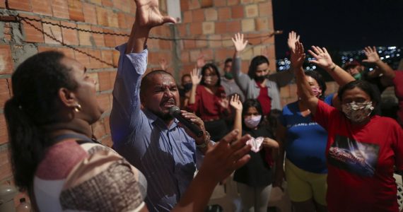 Pastor oferece consolo a pessoas durante o velório de vítimas da Covid-19