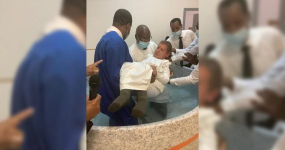 Dependente físico, homem recebe ajuda de fiéis para se batizar nas águas